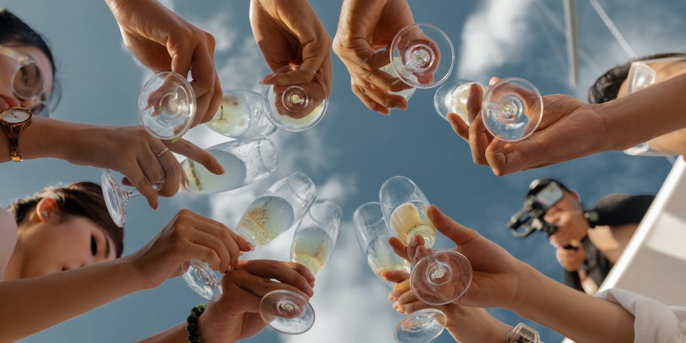 people holding clear glass bottles during daytime